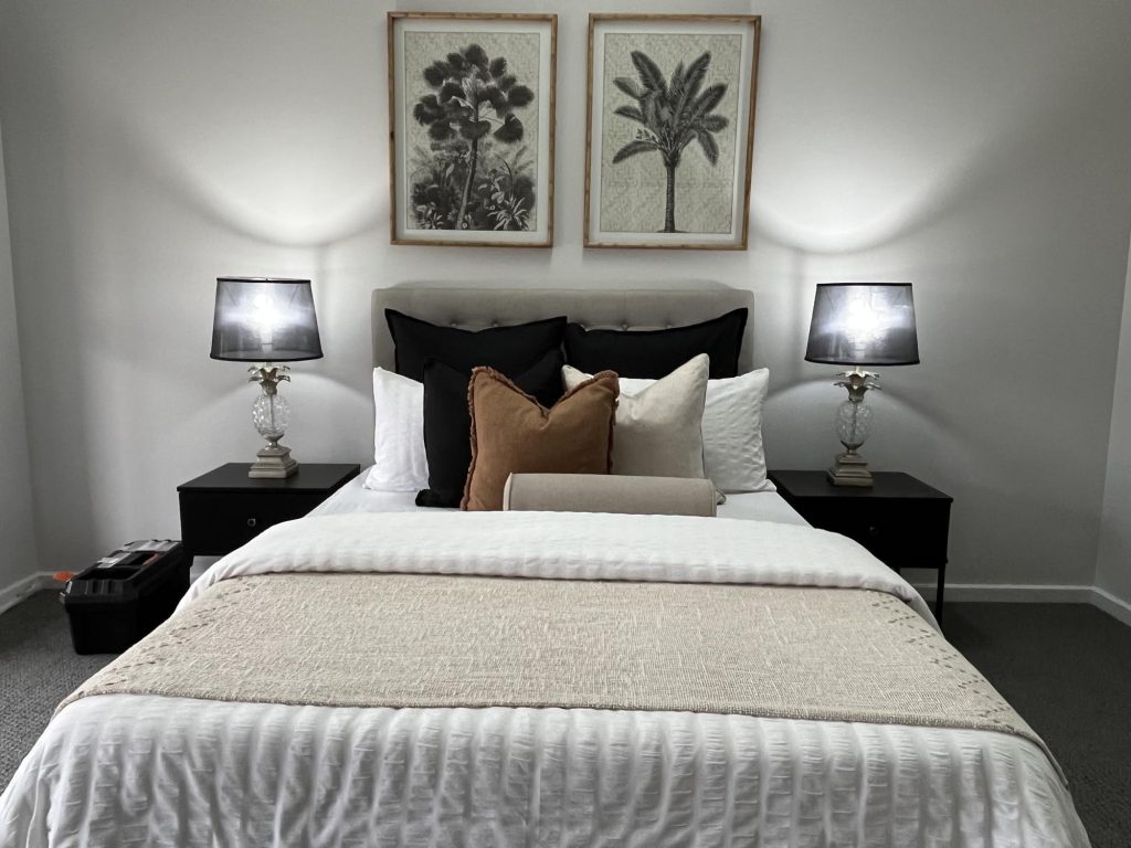 A bedroom with a white bed and black pillows.
