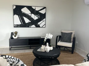 A living room with a black and white painting on the wall.