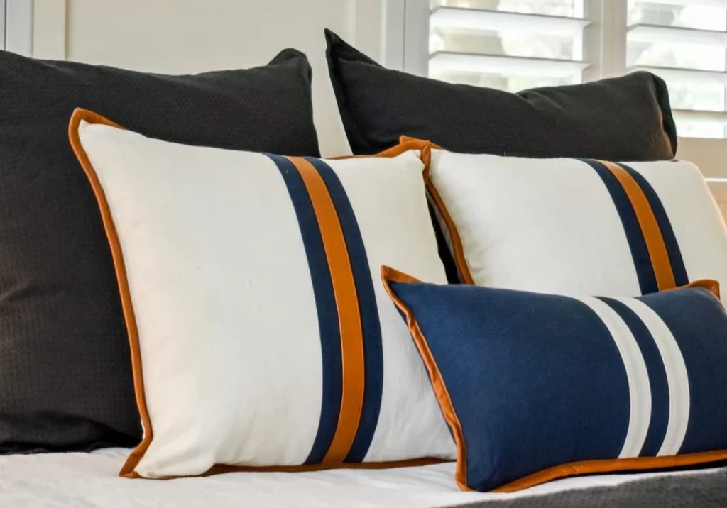 A bed with blue, white and orange striped pillows.